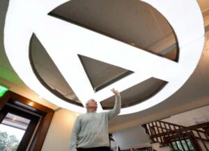 Steve Reymann stands underneath the giant 'A' from the Atlantic Foundry sign that hangs as a light fixture.