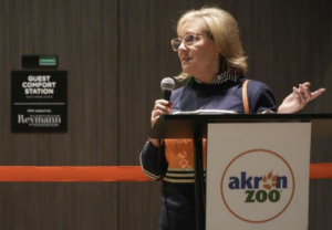 Margaret Reymann Skinner speaks at a podium during the Akron Zoo Guest Comfort Station ribbon-cutting ceremony.